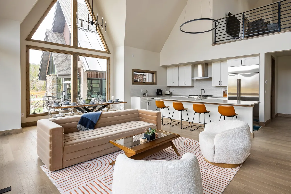 A spacious living area featuring large windows with picturesque views, a comfortable sofa perfect for relaxing after outdoor adventures, and a stylish dining area. The abundance of natural light and the inviting atmosphere create an ideal setting for socializing, unwinding, and enjoying the surroundings.