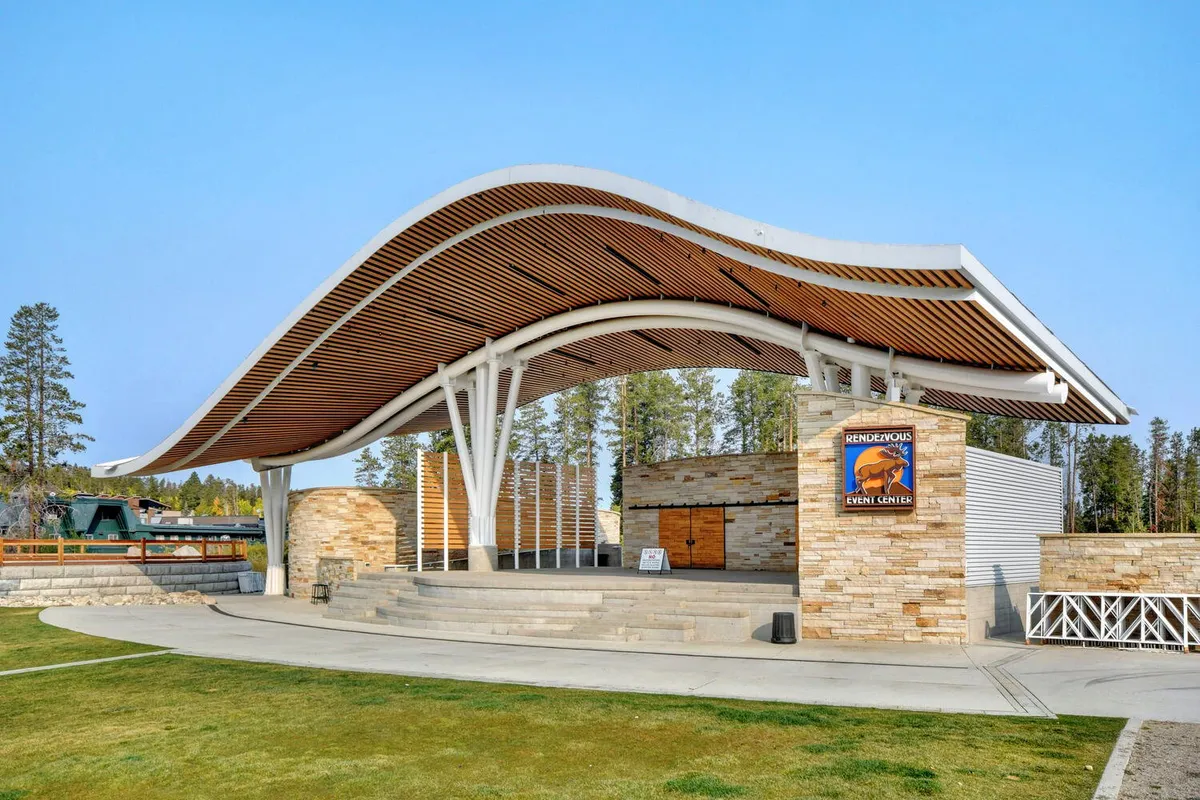 This image captures the exterior of the Rendezvous Event Center at Hideaway Park, featuring its modern curved roof, stone walls, and clear event center signage. The open space suggests a lively hub for concerts, festivals, and community gatherings, perfectly reflecting the vibrant, walkable downtown atmosphere discussed in the section.