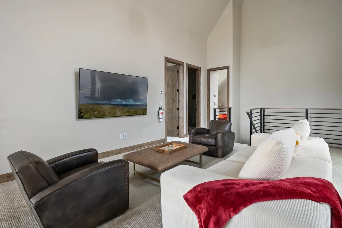 A contemporary living space featuring a plush sofa, inviting armchairs, a coffee table, and a large TV displaying a scenic landscape. The arrangement encourages group entertainment, movie nights, and intimate conversations.