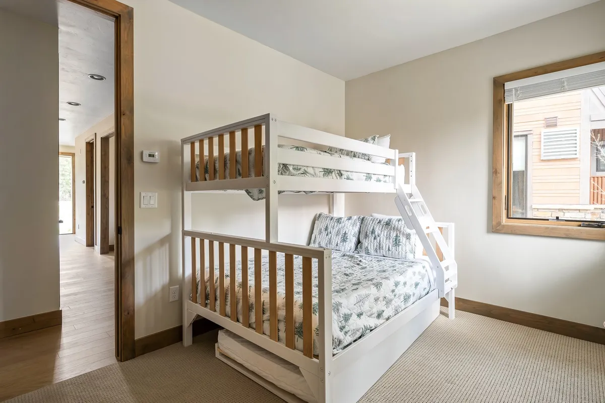 A playful and family-friendly bunk room with a window, cheerful textile patterns, and a sturdy bunk bed. The space is designed to delight children or cousins, adding a sense of fun and togetherness to the home.