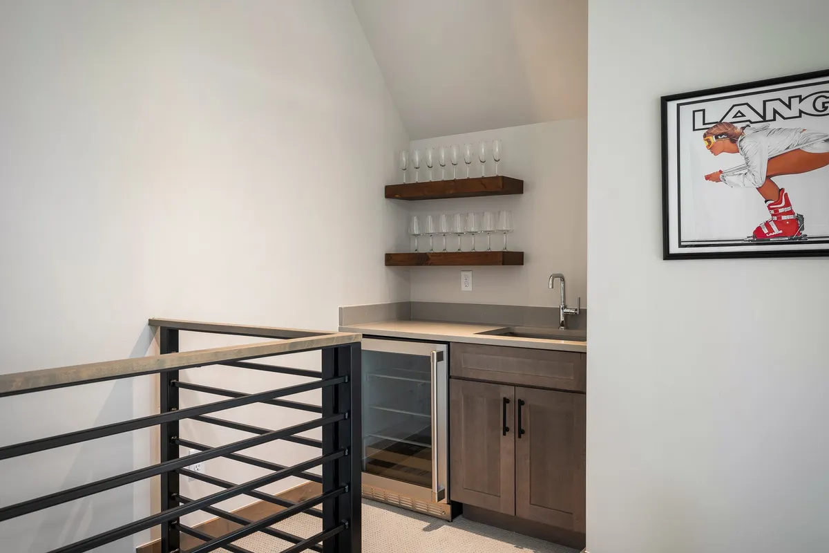 A sophisticated wet bar area with a wine cooler, glass shelves, and eye-catching artwork. The setting is perfect for preparing cocktails or enjoying drinks with friends after a day exploring the mountain.